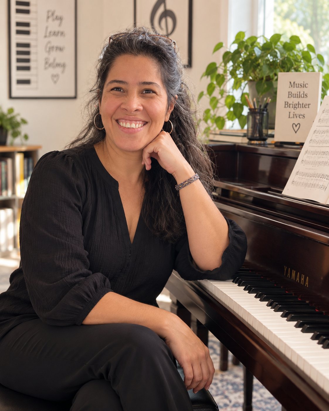 Mayda Cuellar Bustamante seated beside an upright piano in her studio